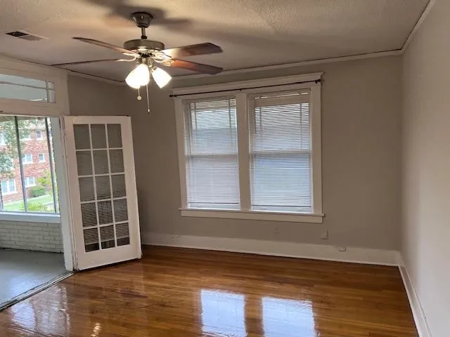 an empty room with wooden floor fan and windows