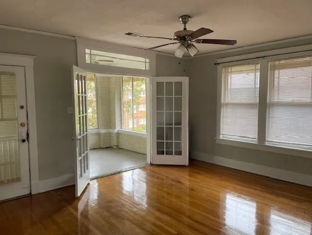 a view of an empty room with wooden floor and a window