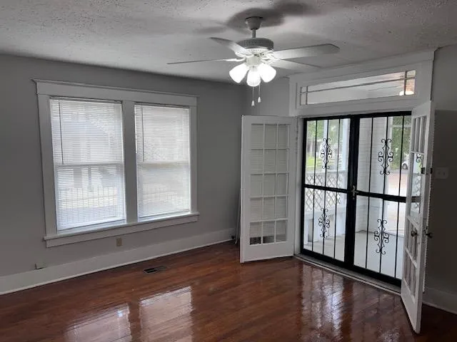 a view of an empty room with wooden floor and a window