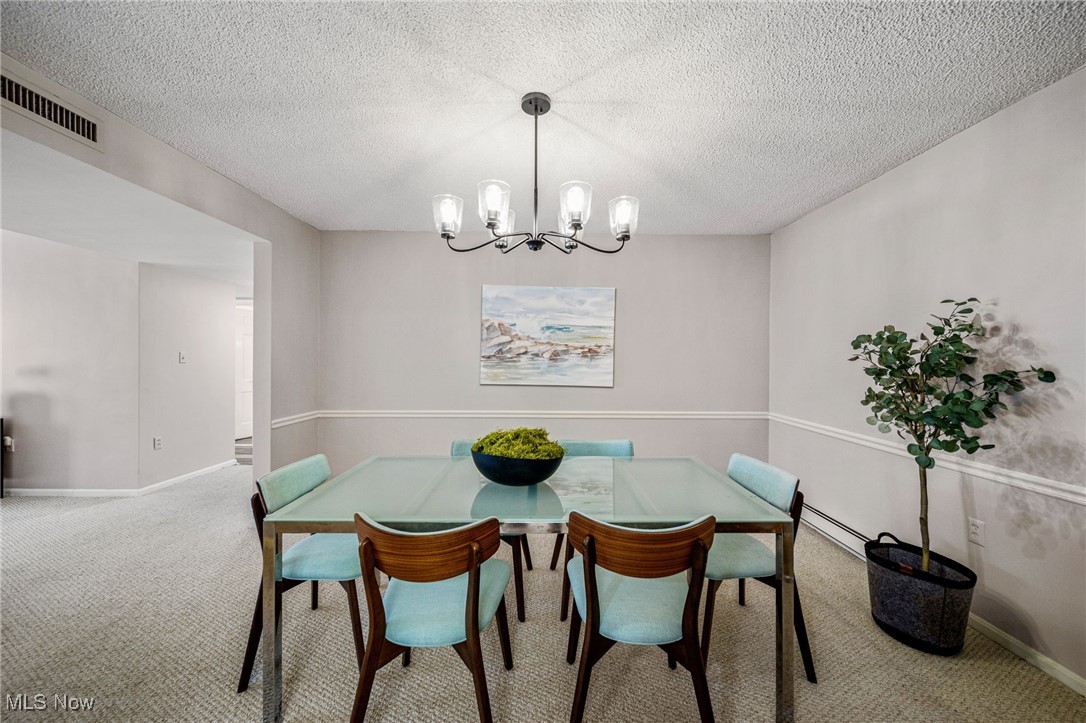 2365 Covington Road, Unit 225 Akron, OH 44313 - Photo 5 of 36 Carpeted dining space with an inviting chandelier, baseboards, visible vents, and a textured ceiling