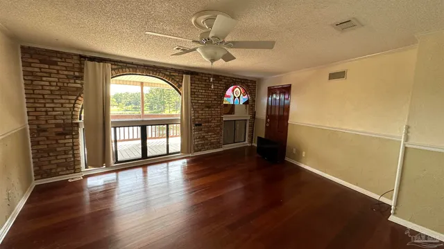 an empty room with wooden floor fan and windows