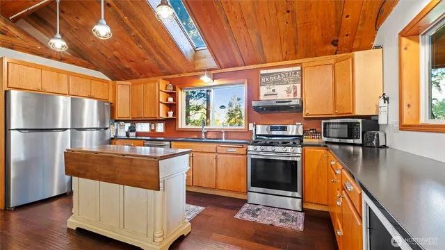 a kitchen with stainless steel appliances granite countertop a stove a refrigerator a sink dishwasher and a stove with wooden floor