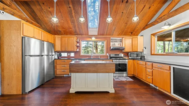 a large kitchen with stainless steel appliances granite countertop a refrigerator a sink dishwasher a stove and white countertops with wooden floor