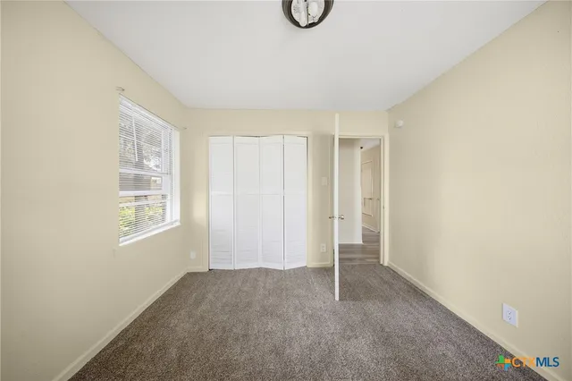 a view of an empty room with window and closet area