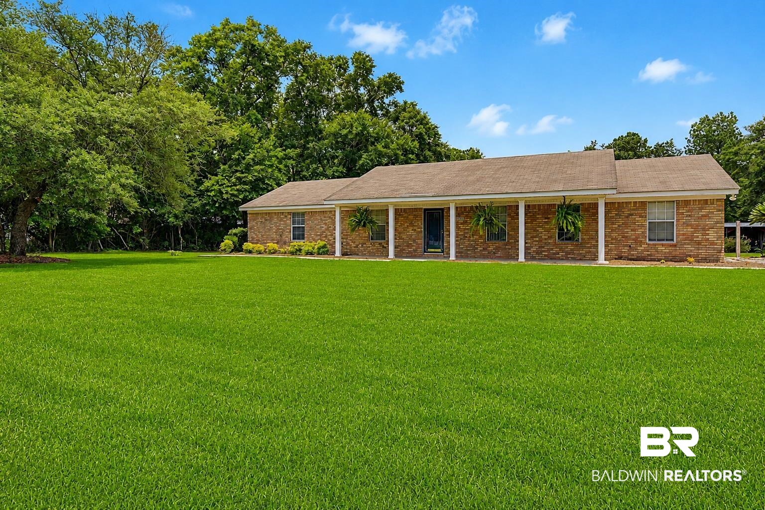 22963 Highway 98 Foley, AL 36535 - Photo 1 of 52 Brick exterior residence featuring a covered front porch with white columns, a dark entry door, and a shingle roof
