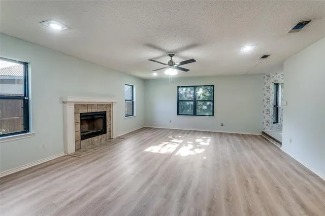 an empty room with windows and fireplace