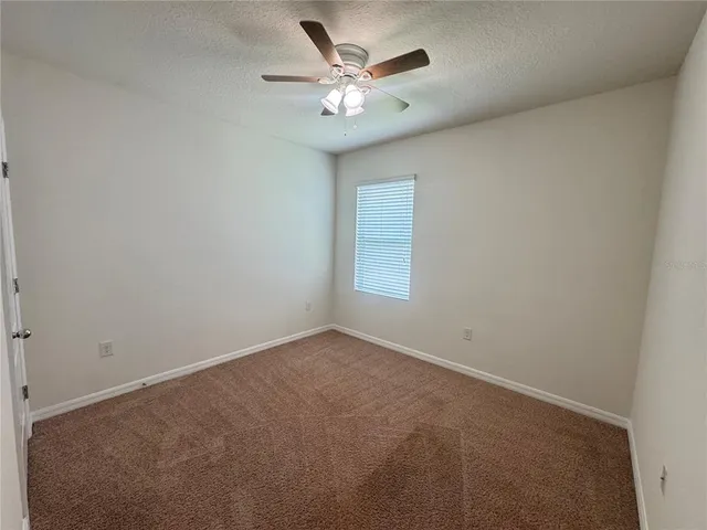 an empty room with a window and a ceiling fan