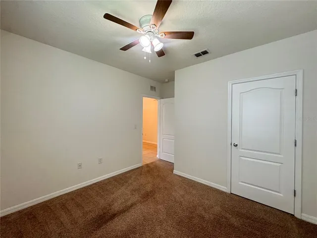 an empty room with closet and a ceiling fan