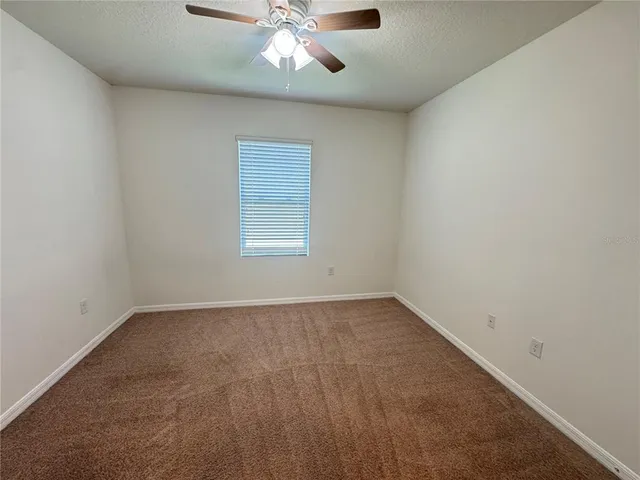 an empty room with a chandelier fan and windows