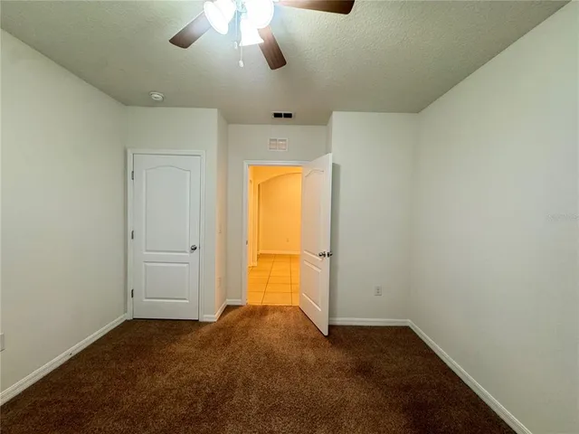 an empty room with a window and chandelier fan