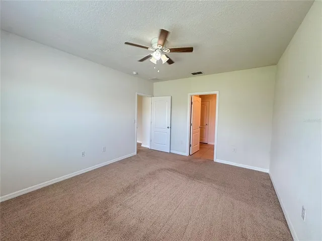 an empty room with ceiling fan and window