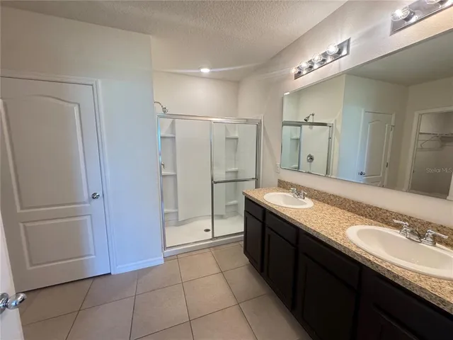 a spacious bathroom with a granite countertop sink a mirror and a bathtub