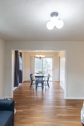 a dining room with wooden floor a chandelier a glass table and chairs