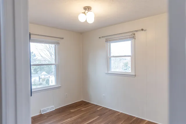 a view of a bedroom with wooden floor and a window