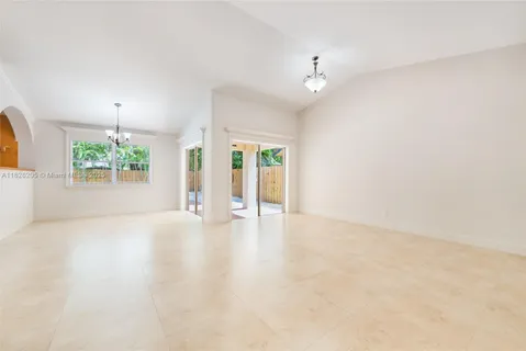 an empty room with windows and chandelier fan