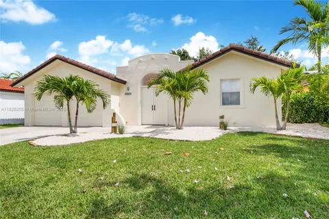 a view of a white house with a big yard and potted plants