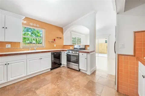 a kitchen with stainless steel appliances a stove a sink and white cabinets
