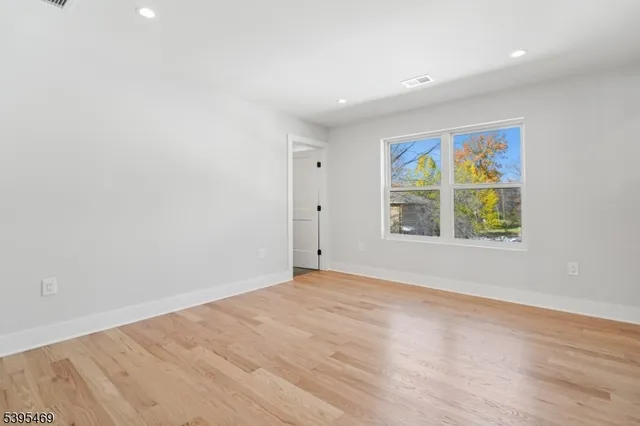 a view of an empty room with a window and a wooden floor