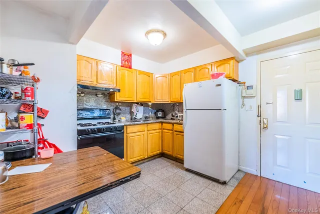 a kitchen with refrigerator a stove and a wooden floor