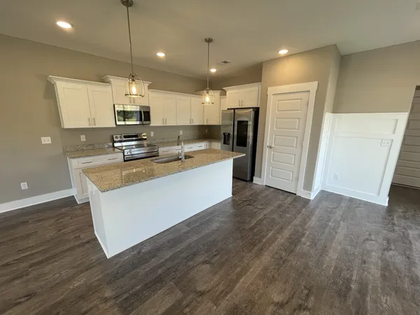 a large kitchen with stainless steel appliances a large counter top a sink a refrigerator and a window