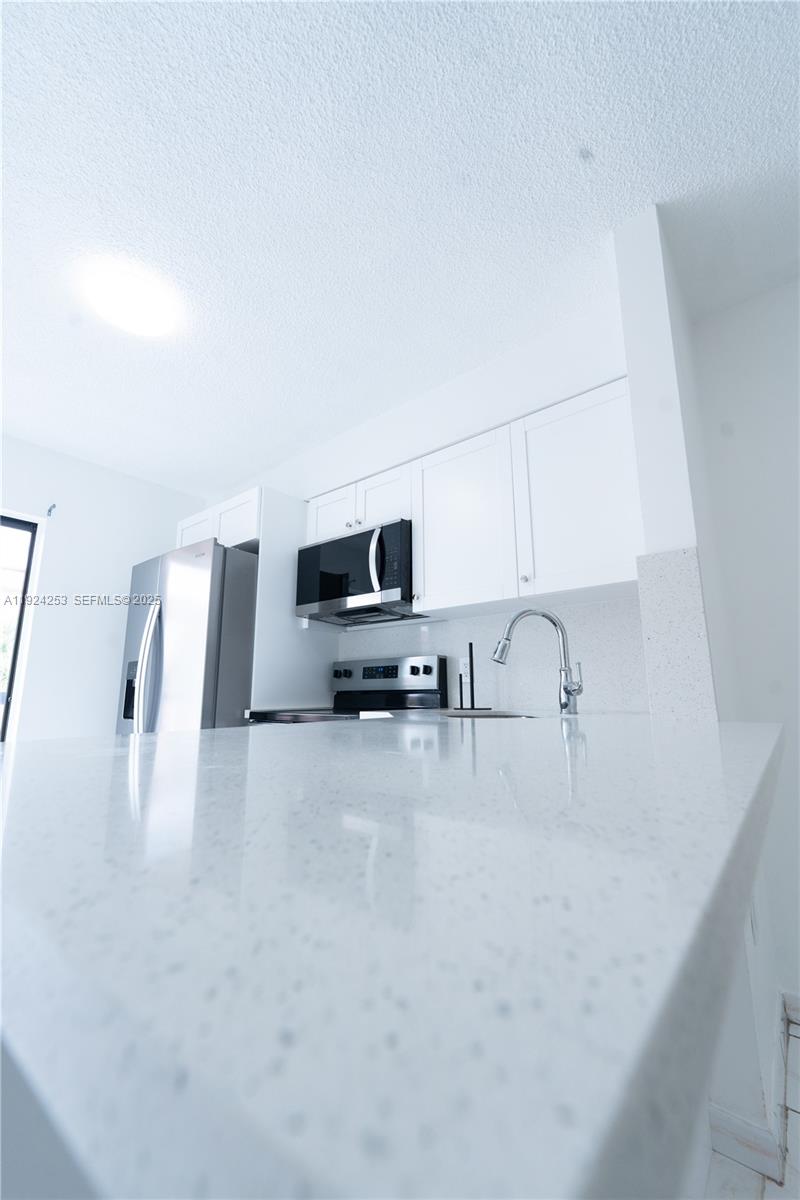 5300 West 21st Court, Unit 311 Hialeah, FL 33016 - Photo 3 of 10 a kitchen with furniture a refrigerator and a sink