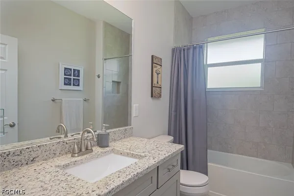 a bathroom with a granite countertop sink toilet and shower