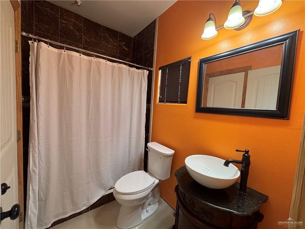 45 Zinnia Street Rio Grande City, TX 78582 - Photo 18 of 31 a bathroom with a toilet a sink and a shower curtain