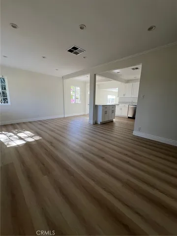 a view of an empty room with window and wooden floor