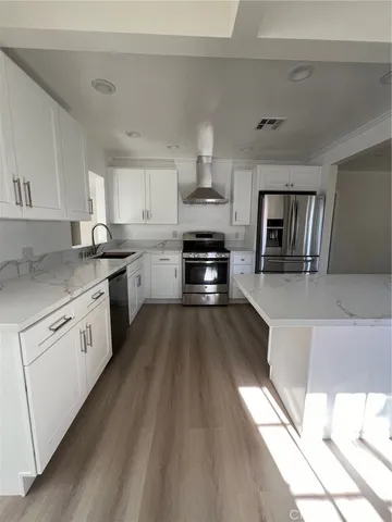 a kitchen with granite countertop a stove top oven a sink dishwasher and white cabinets with wooden floor