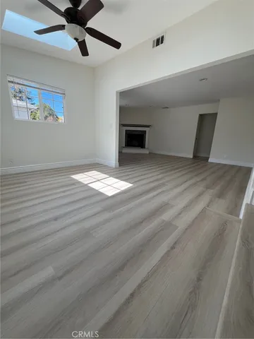 a view of empty room with wooden floor and fan