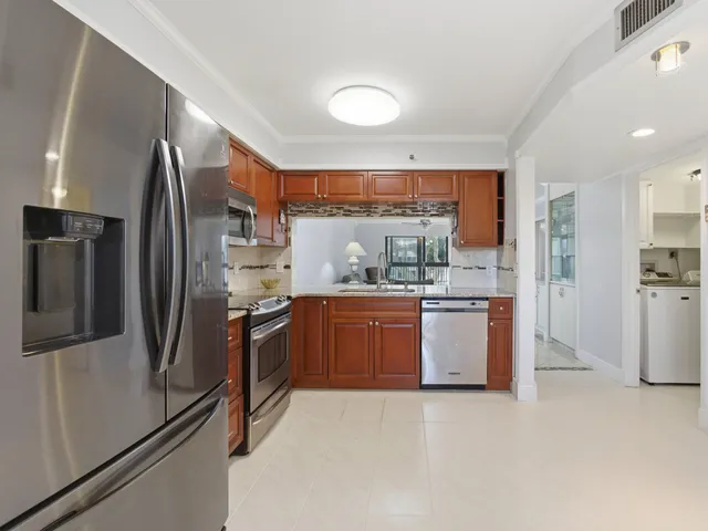 a kitchen with stainless steel appliances granite countertop a stove a refrigerator a kitchen island a table and chairs