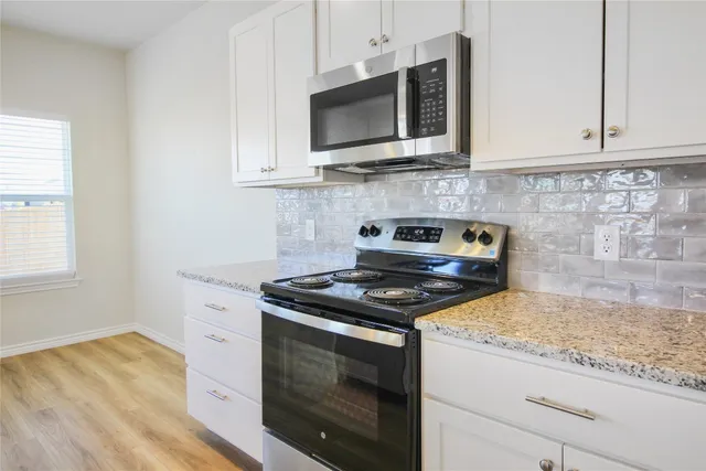 a kitchen with stainless steel appliances granite countertop a refrigerator a stove and a sink