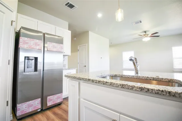 a kitchen with granite countertop cabinets stainless steel appliances and wooden floor