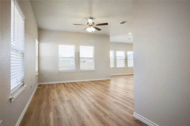 a view of an empty room with a window and wooden floor