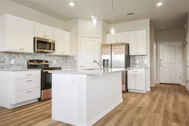 a kitchen with white cabinets and stainless steel appliances