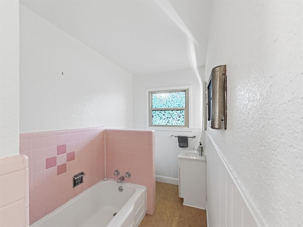 2137 Lenamon Street Waco, TX 76710 - Photo 9 of 29 Bathroom featuring a white bathtub, pink tiled surround, a window with obscure glass, and a vanity with a white basin