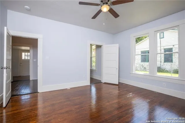 a view of an empty room with wooden floor and a window