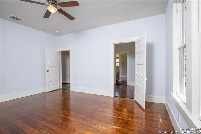 an empty room with wooden floor and windows