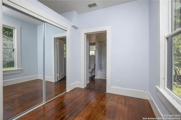 an empty room with wooden floor and windows