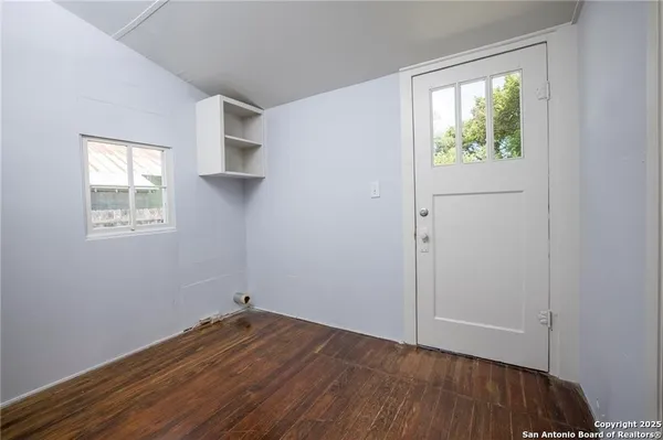 an empty room with wooden floor and windows