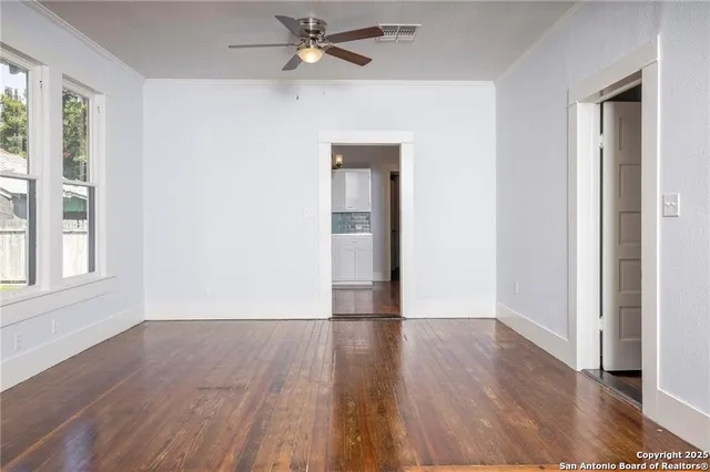 a view of empty room with wooden floor and fan