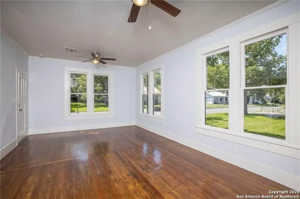 a view of an empty room with window and wooden floor