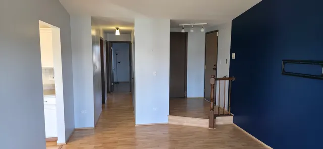 a view of a hallway with wooden floor and a bathroom