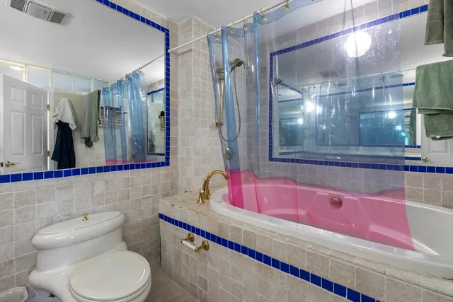 a bathroom with a granite countertop bathtub sink vanity mirror and toilet
