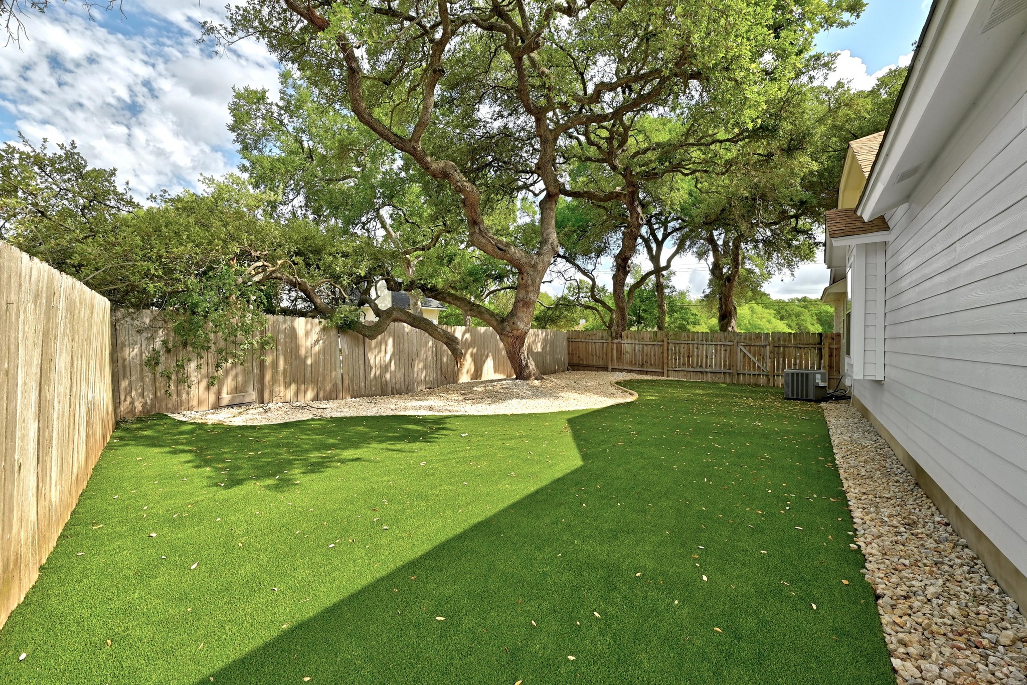 5807 Convict Hill Road Austin, TX 78749 - Photo 26 of 27 The side yard is shaded by mature oaks and framed with decorative rock landscaping, a serene, low-maintenance space for lounging or pets.