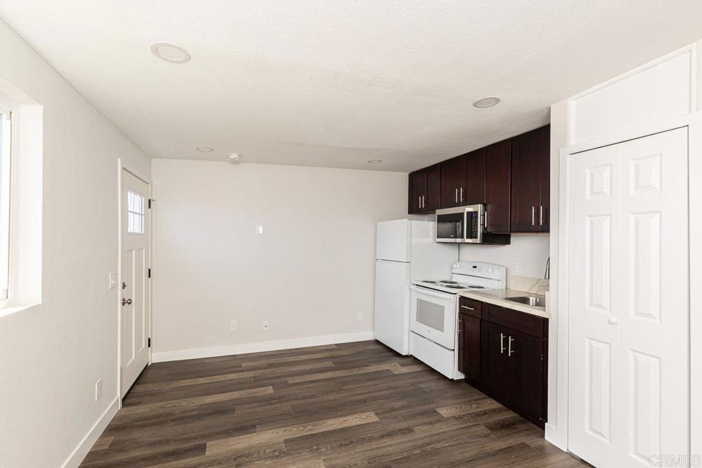 1020 41st Street San Diego, CA 92102 - Photo 17 of 39 a kitchen with stainless steel appliances a stove top oven a sink a refrigerator white cabinets and wooden floor