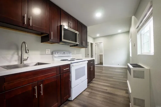 a large kitchen with stainless steel appliances wooden cabinets a sink and a stove
