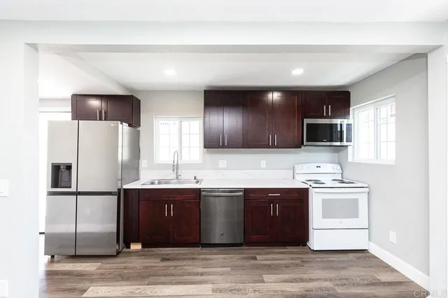 a kitchen with stainless steel appliances granite countertop a sink a stove a refrigerator and cabinets