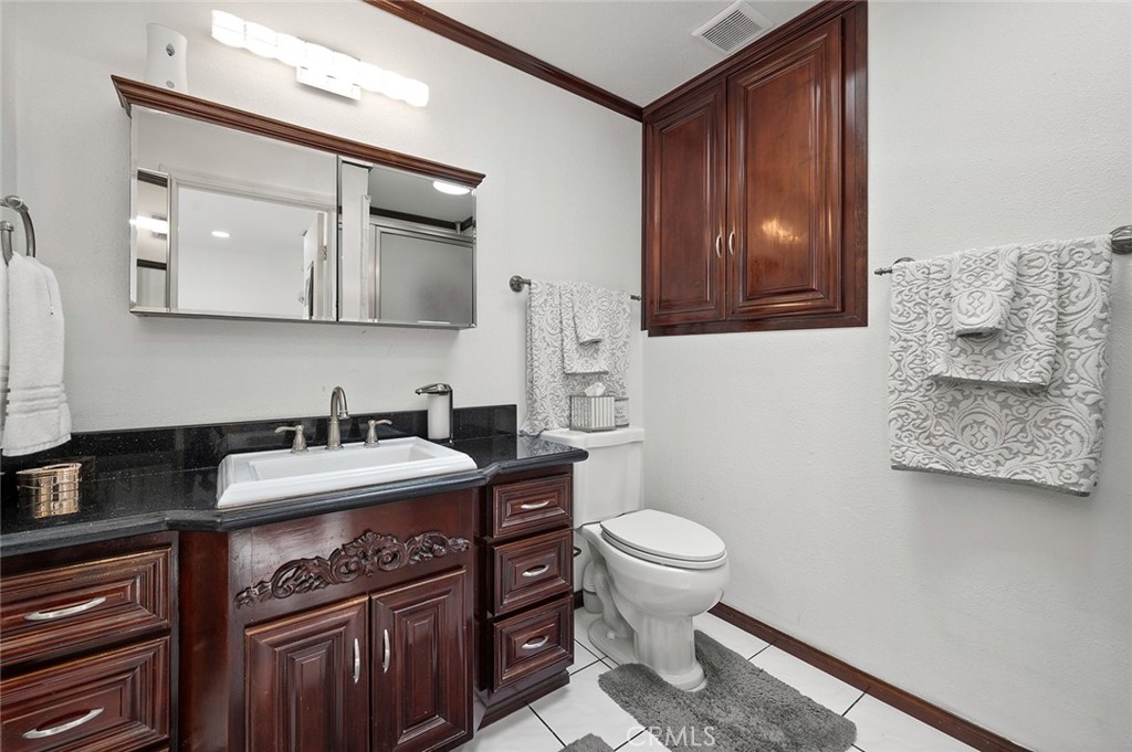 27447 Cypress Street Highland, CA 92346 - Photo 24 of 42 a bathroom with a granite countertop toilet sink and mirror