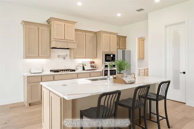 a view of a kitchen with kitchen island wooden floors appliances and center island